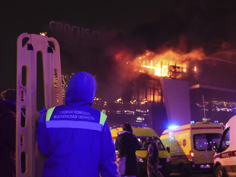 A medic stands near ambulances parked outside the burning building of the Crocus City Hall