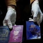 A man displays blood-stained British, Polish, and Australian passports ( Israeli air strike)