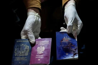 A man displays blood-stained British, Polish, and Australian passports ( Israeli air strike)